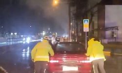 Arızalanan otomobili trafik polisleri yağmurun altında itti